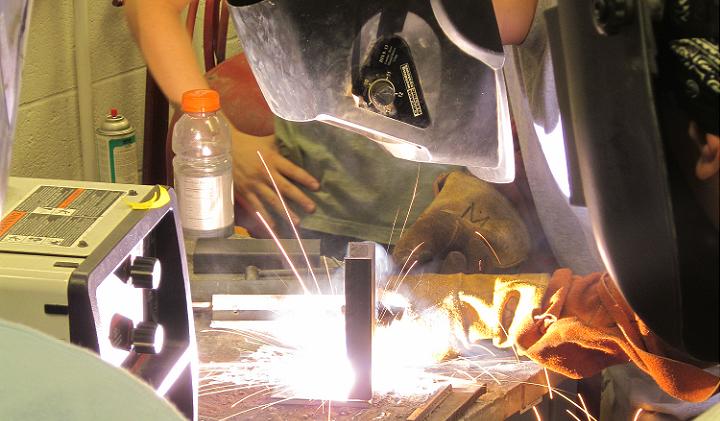 Student welding steel channel onto steel plate