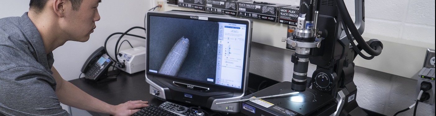 Student looking at fracture surface of a wire under a microscope, Photo Credit: Barbara Alper
